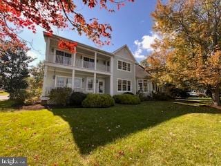 view of front property with a front lawn and a balcony