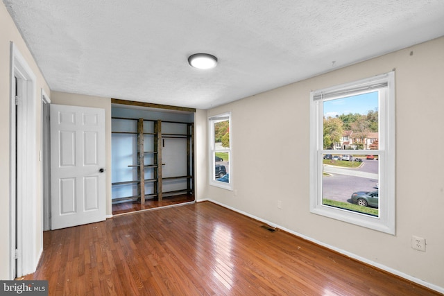 unfurnished bedroom with a textured ceiling and dark hardwood / wood-style flooring