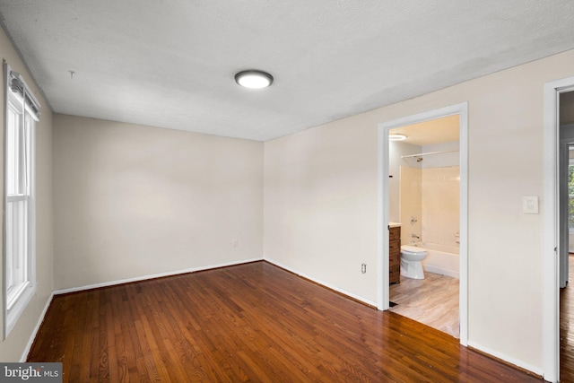 empty room featuring a wealth of natural light, a textured ceiling, and hardwood / wood-style flooring