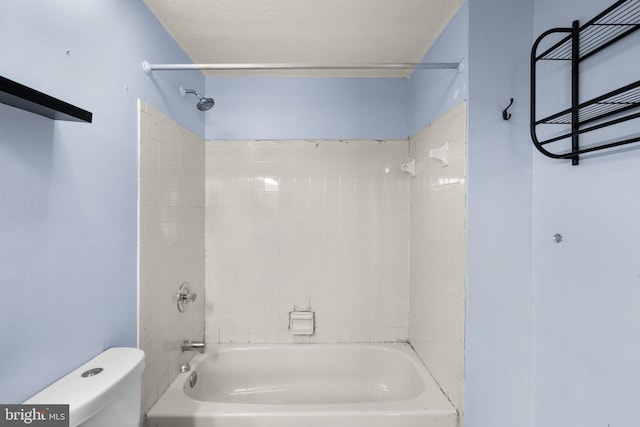 bathroom with toilet, tiled shower / bath, and a textured ceiling