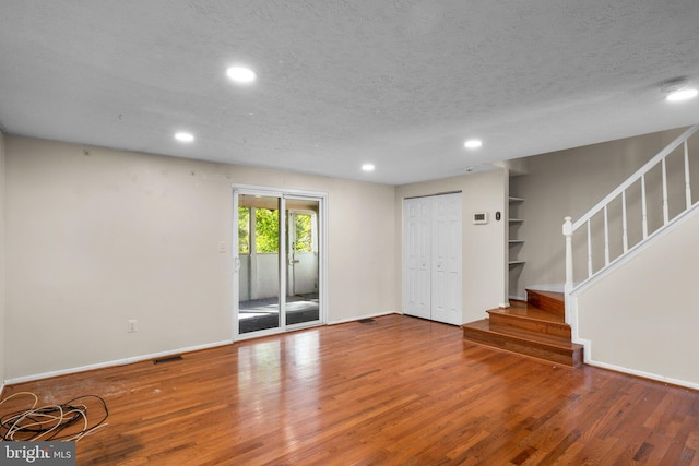 spare room featuring hardwood / wood-style flooring, a textured ceiling, and built in shelves