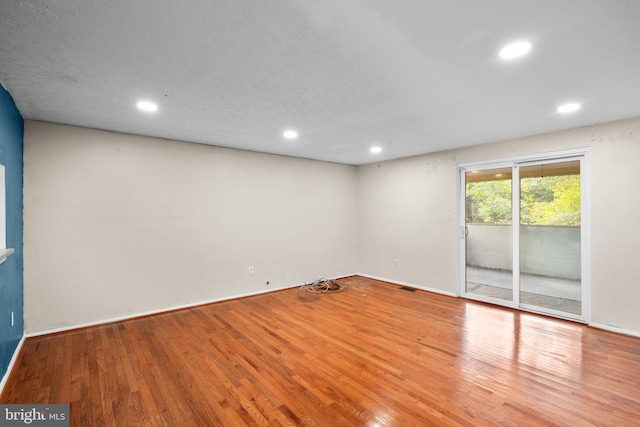 unfurnished room featuring light hardwood / wood-style flooring and a textured ceiling