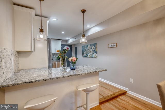 kitchen with white cabinetry, tasteful backsplash, a breakfast bar, and decorative light fixtures