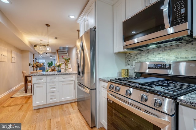 kitchen with tasteful backsplash, appliances with stainless steel finishes, a chandelier, and white cabinets