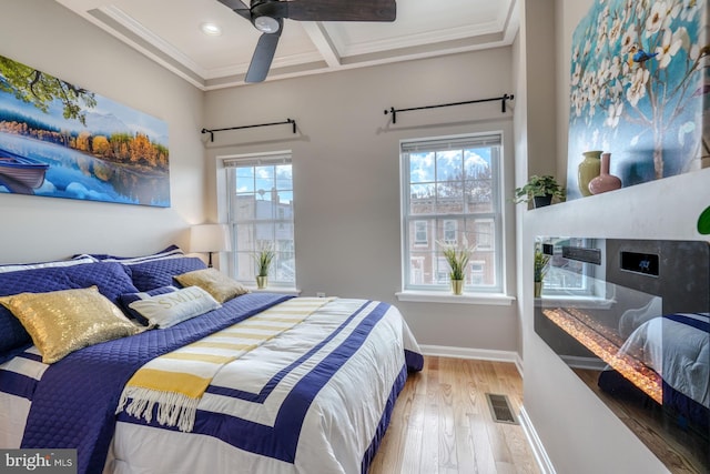 bedroom featuring multiple windows, wood-type flooring, a fireplace, and ceiling fan