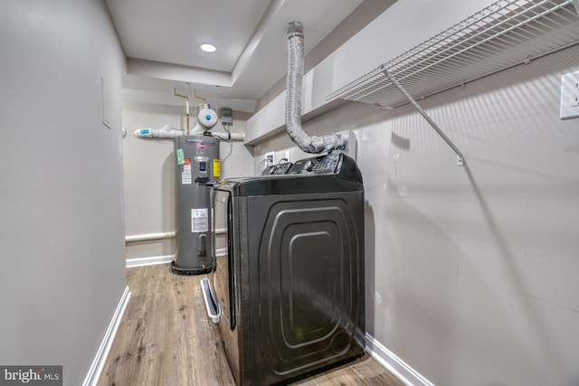 laundry room featuring electric water heater, wood-type flooring, and separate washer and dryer