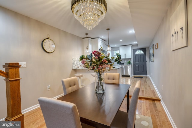 dining space with light hardwood / wood-style flooring and a notable chandelier