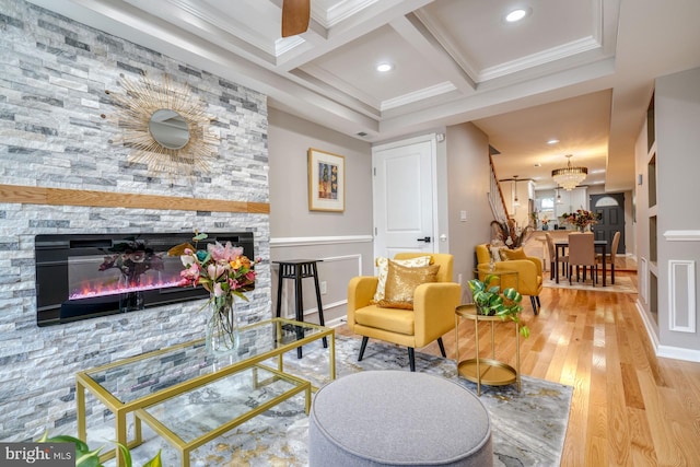 sitting room with ornamental molding, coffered ceiling, a stone fireplace, and light hardwood / wood-style floors