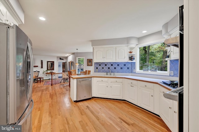 kitchen featuring a wealth of natural light, hanging light fixtures, stainless steel appliances, and white cabinets