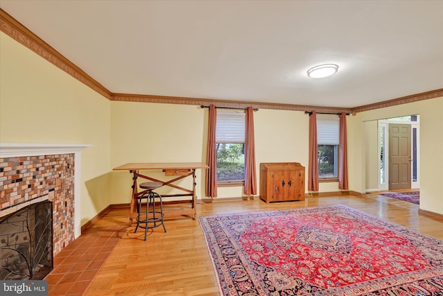 living room with a brick fireplace, light wood-type flooring, and crown molding