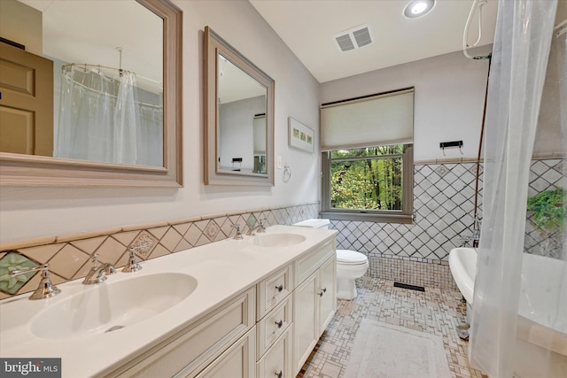 full bathroom with vanity, shower / bath combo with shower curtain, tile walls, tile patterned floors, and toilet