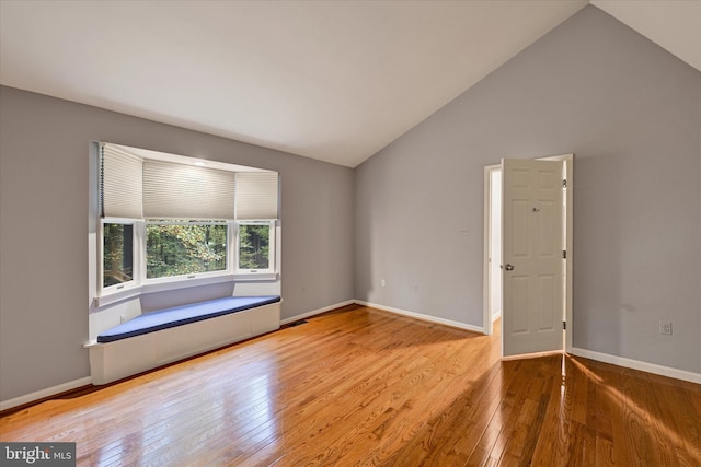 empty room with hardwood / wood-style flooring and high vaulted ceiling