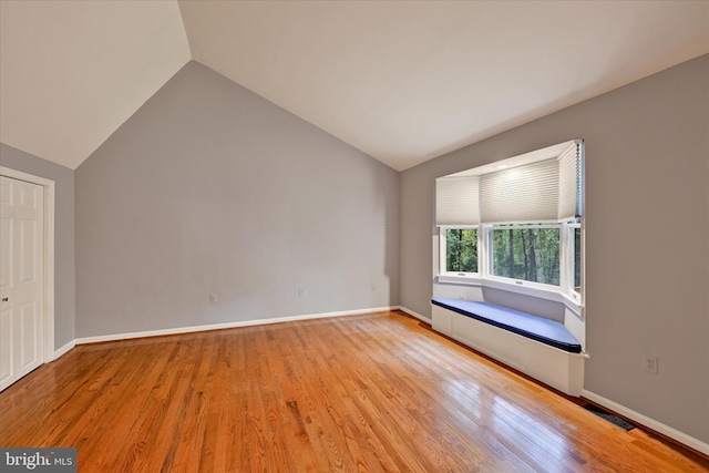 unfurnished room featuring vaulted ceiling and light hardwood / wood-style flooring