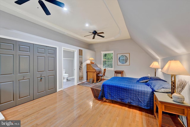 bedroom featuring wood-type flooring, connected bathroom, vaulted ceiling, and ceiling fan