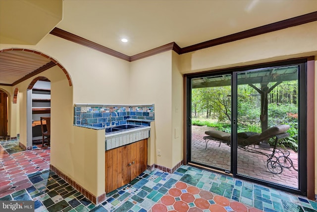 interior space with decorative backsplash, crown molding, and sink