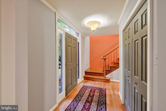 foyer entrance with light hardwood / wood-style floors and crown molding