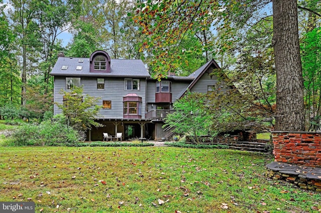 rear view of house featuring a wooden deck and a yard