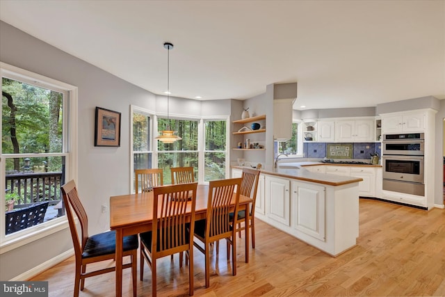 dining room with light hardwood / wood-style floors, sink, and a healthy amount of sunlight