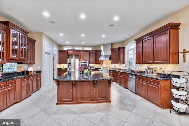 kitchen with a breakfast bar, appliances with stainless steel finishes, a kitchen island, and wall chimney exhaust hood