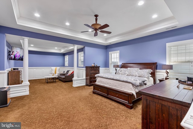 bedroom featuring a tray ceiling, decorative columns, light colored carpet, and ceiling fan