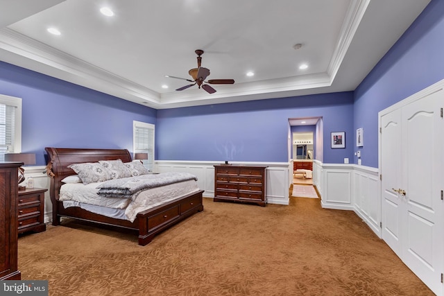 carpeted bedroom with ceiling fan, a raised ceiling, and ornamental molding