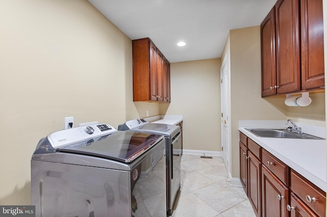 washroom featuring cabinets, washing machine and dryer, light tile patterned flooring, and sink