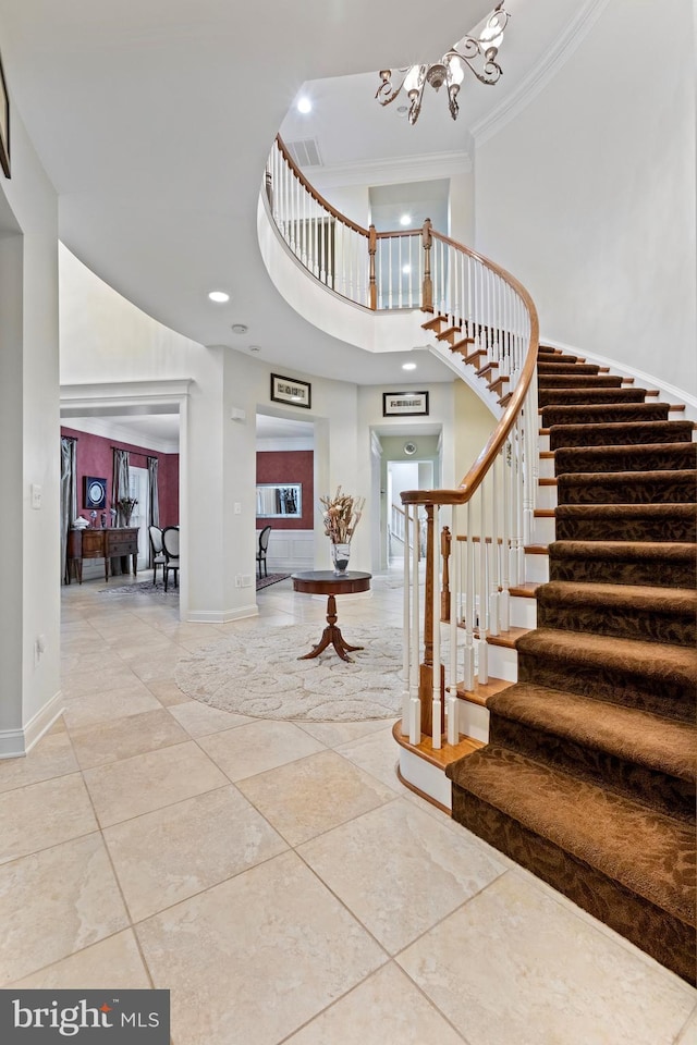 foyer with a high ceiling, an inviting chandelier, and ornamental molding