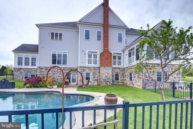 view of swimming pool featuring a yard and french doors