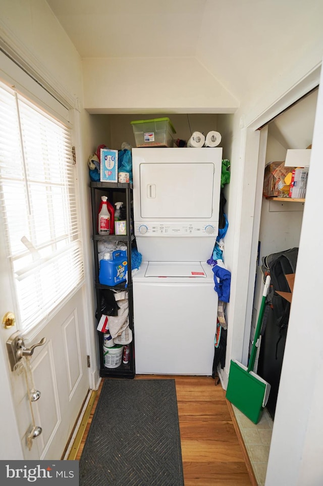 laundry room with stacked washer and clothes dryer and light wood-type flooring