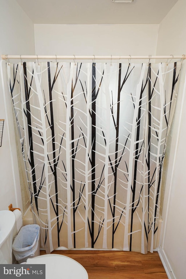 bathroom with hardwood / wood-style floors, toilet, and walk in shower