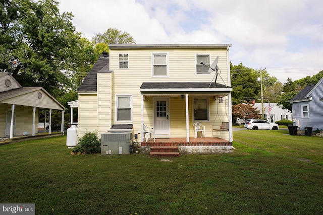 back of property featuring covered porch and a lawn