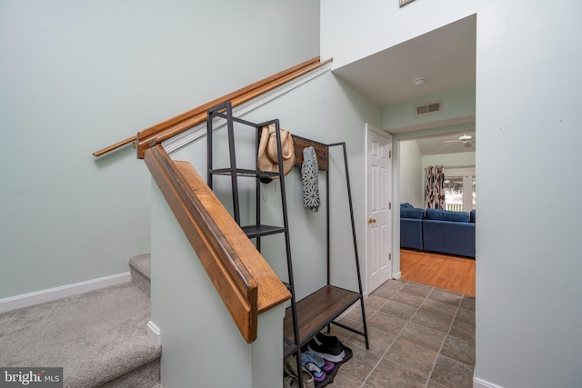 stairs featuring ceiling fan and carpet floors