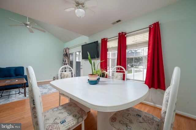 dining space with vaulted ceiling, hardwood / wood-style flooring, and ceiling fan