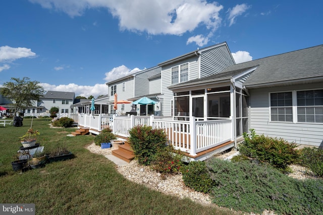 back of property with a sunroom, a lawn, and a deck