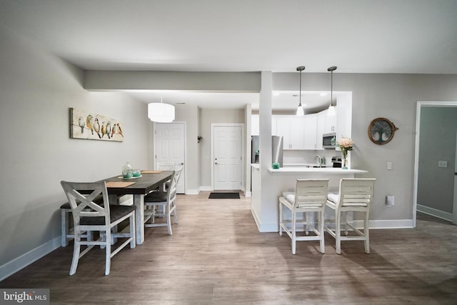 kitchen with kitchen peninsula, pendant lighting, stainless steel appliances, and white cabinetry