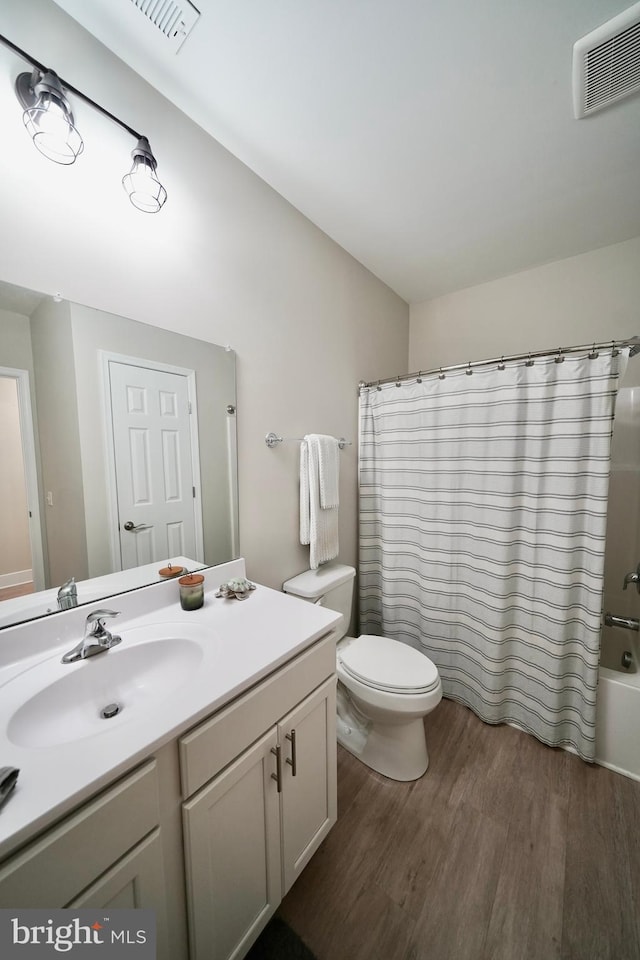 full bathroom with hardwood / wood-style flooring, vanity, toilet, and shower / bath combo with shower curtain