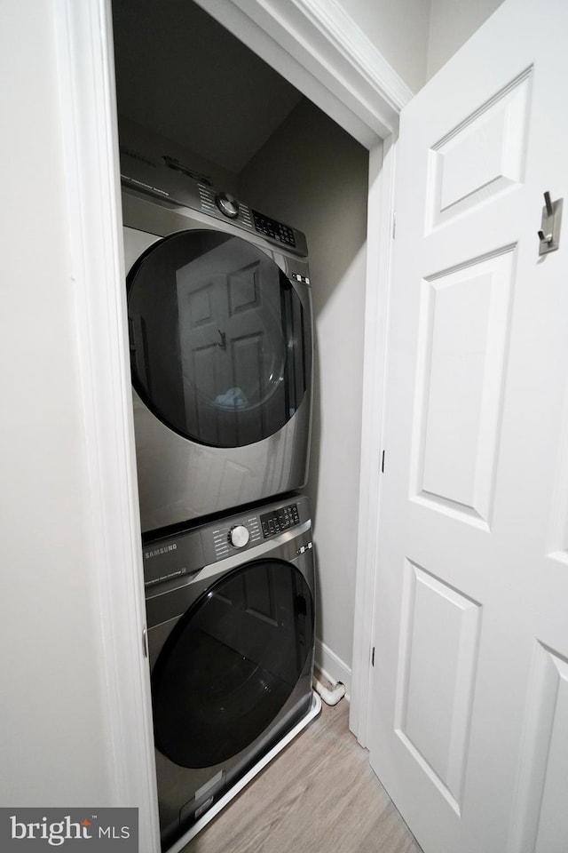 laundry area featuring light hardwood / wood-style floors and stacked washer and clothes dryer