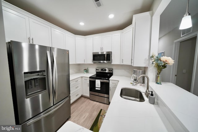 kitchen featuring sink, light stone counters, decorative light fixtures, white cabinets, and appliances with stainless steel finishes