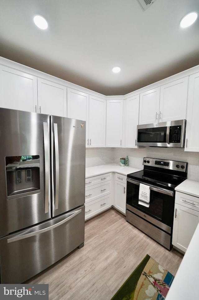 kitchen featuring white cabinets, light wood-type flooring, and stainless steel appliances