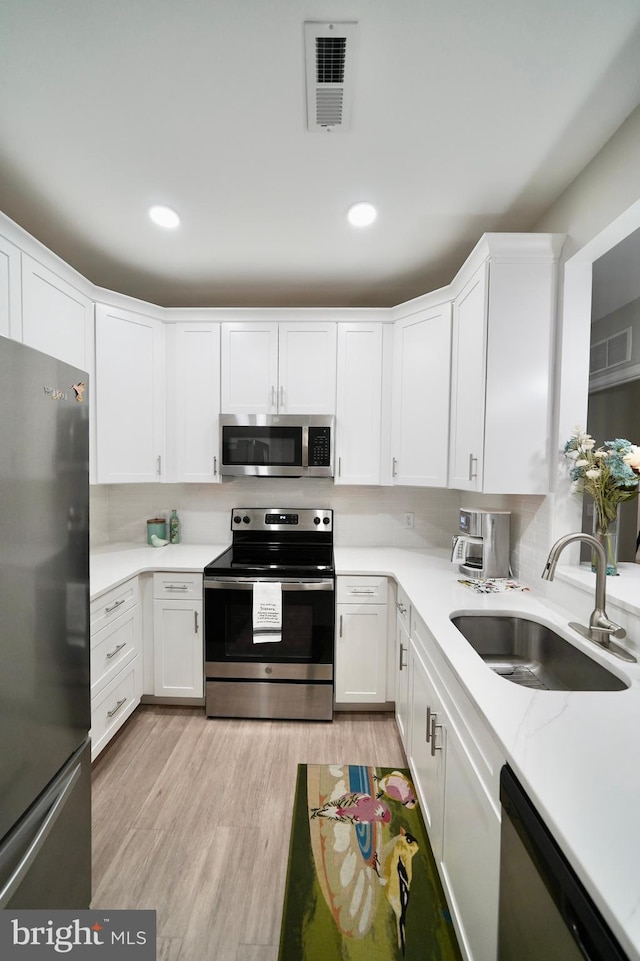 kitchen with white cabinets, sink, light wood-type flooring, and stainless steel appliances