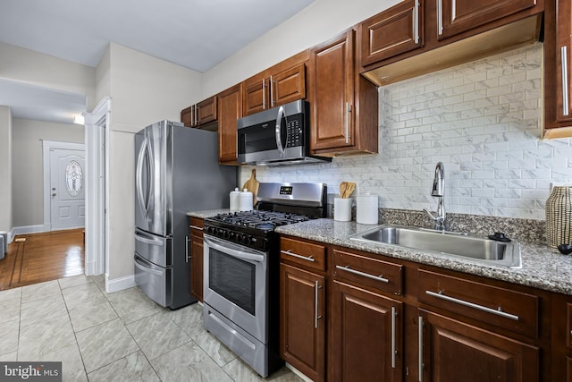 kitchen featuring light hardwood / wood-style flooring, stainless steel appliances, backsplash, sink, and light stone countertops