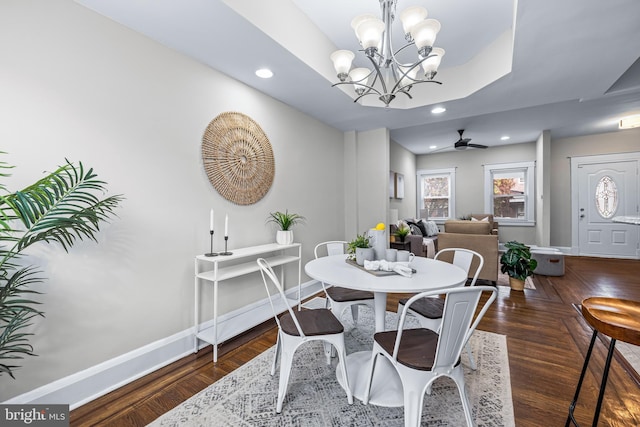 dining room with ceiling fan with notable chandelier and dark hardwood / wood-style flooring