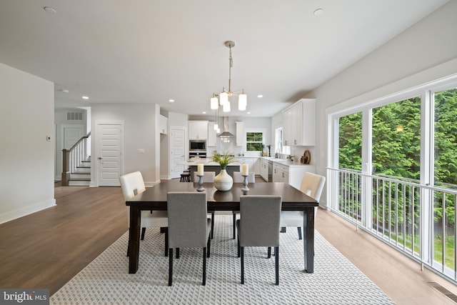 dining space with light hardwood / wood-style floors and a notable chandelier