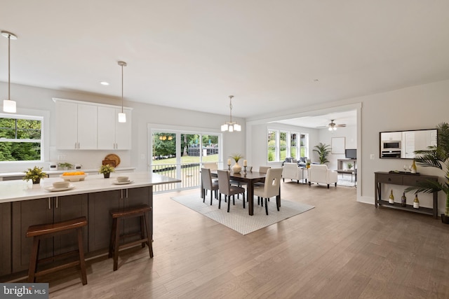 dining space with ceiling fan with notable chandelier and dark hardwood / wood-style flooring