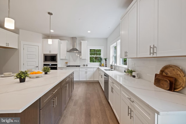 kitchen featuring stainless steel appliances, wall chimney exhaust hood, pendant lighting, white cabinets, and dark wood-type flooring