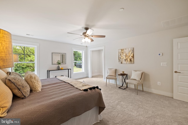 bedroom featuring multiple windows, light colored carpet, and ceiling fan