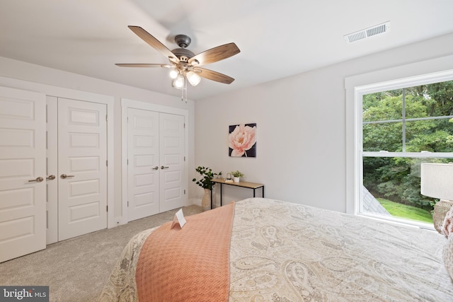 bedroom featuring ceiling fan, carpet flooring, and two closets