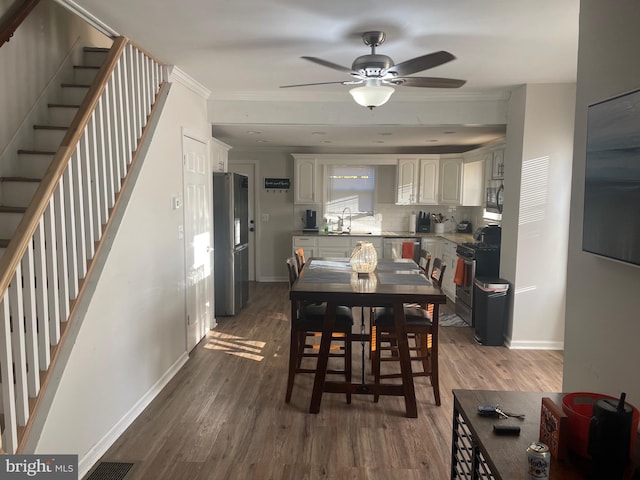 dining area with ornamental molding, ceiling fan, sink, and dark hardwood / wood-style flooring