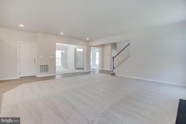 unfurnished living room with light carpet and a notable chandelier