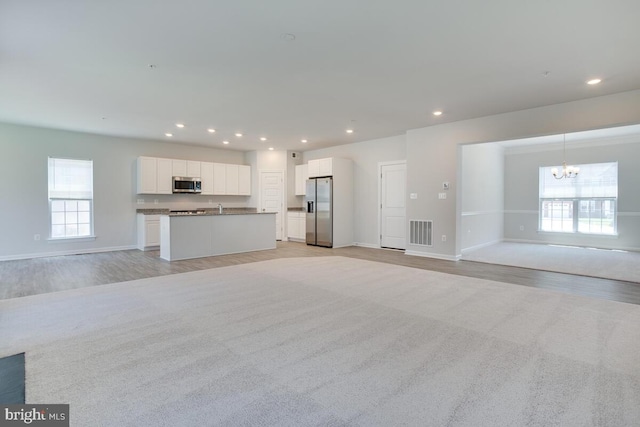 unfurnished living room with light wood-type flooring, a wealth of natural light, and a chandelier